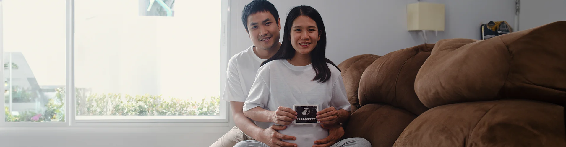 young-asian-pregnant-couple-show-looking-ultrasound-photo-baby-belly-mom-dad-feeling-happy-smiling-peaceful-while-take-care-child-lying-sofa-living-room-home copy